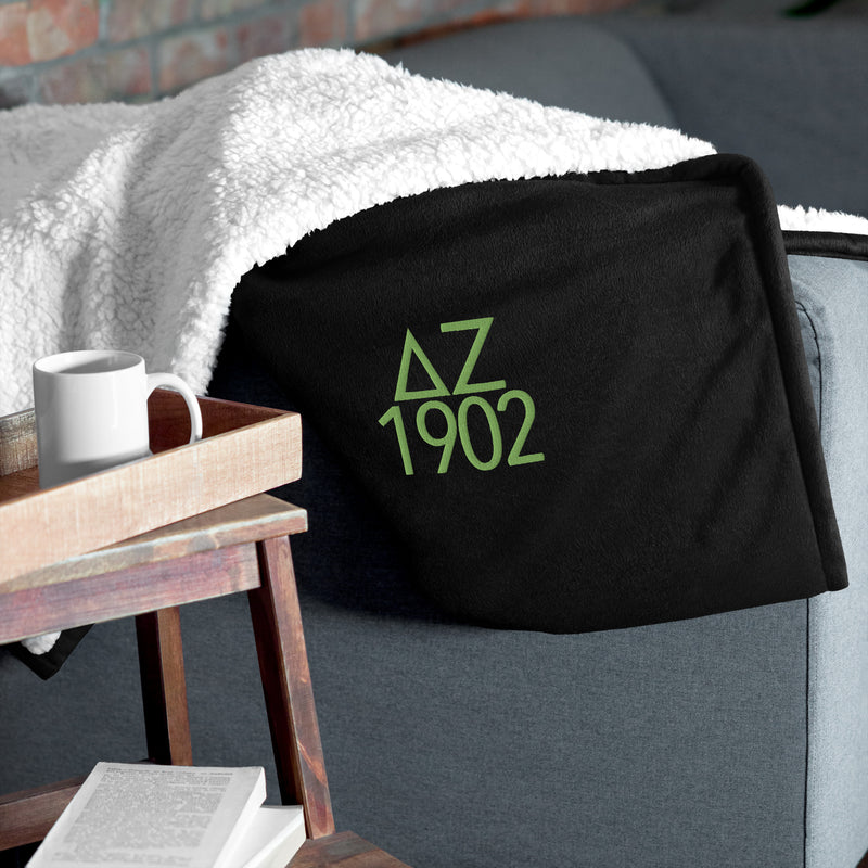 Delta Zeta Plush Embroidered Sherpa Blanket in black on couch