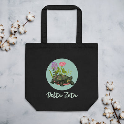 Delta Zeta Turtle Tote Bag in black shown flat with cotton blossoms