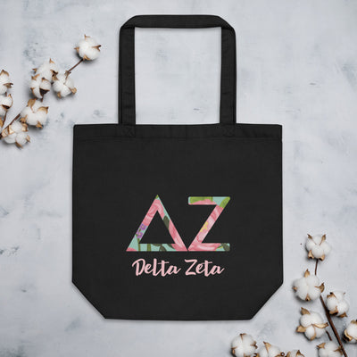 Delta Zeta Sorority Tote Bag with filled letters and sorority name on black bag shown flat with cotton blossoms