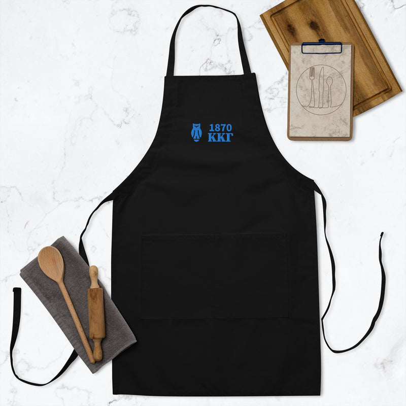 Kappa Kappa Gamma 1870 Owl Embroidered Apron in black shown with kitchen utensils