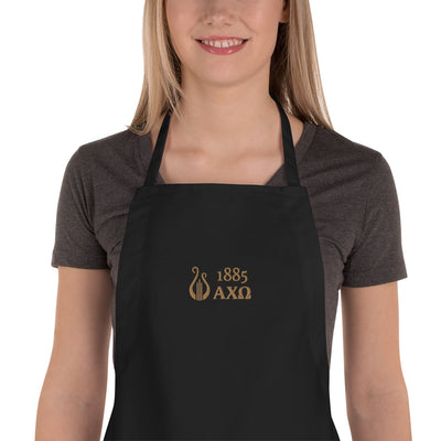 Alpha Chi Omega 1885 Lyre Embroidered Apron in black zoomed in on young woman