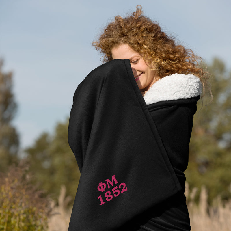 Phi Mu 1852 Embroidered Sherpa Blanket in black wrapped around woman