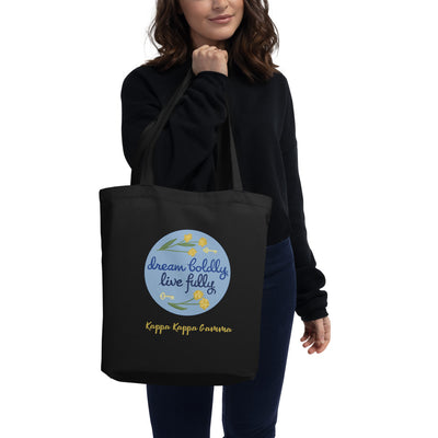 Kappa Kappa Gamma Dream Boldly. Live Fully. motto printed on a black canvas bag shown in model's hand
