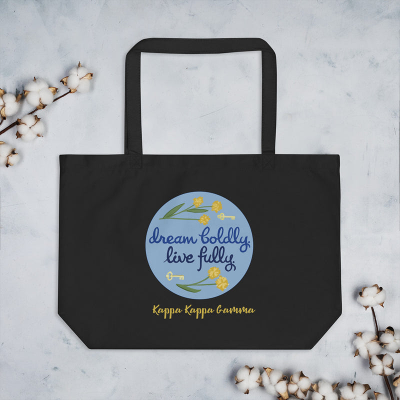 Kappa Kappa Gamma Sorority Motto Dream Boldly. Live Fully. printed on black canvas shopping tote shown flat with cotton blossoms
