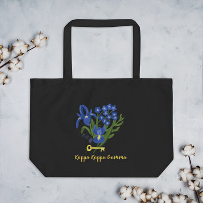 Kappa Kappa Gamma Fleur de key design shown in full view printed on the front of a black organic cotton tote surrounding by cotton blossoms