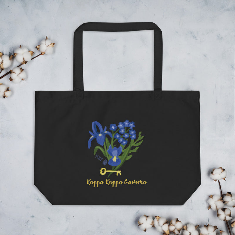 Kappa Kappa Gamma Fleur de key design shown in full view printed on the front of a black organic cotton tote surrounding by cotton blossoms