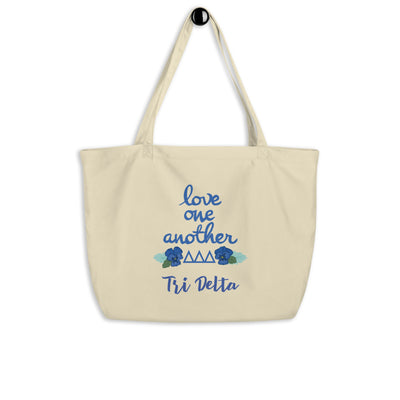 Tri Delta Love One Another Large Organic Tote Bag shown in oyster on a hook