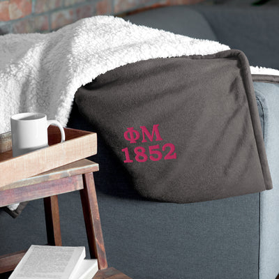 Phi Mu 1852 Embroidered Sherpa Blanket in gray on couch