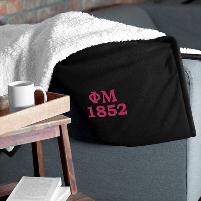 Phi Mu 1852 Embroidered Sherpa Blanket on couch in black