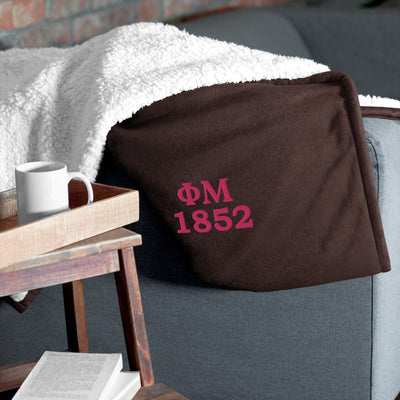 Phi Mu 1852 Embroidered Sherpa Blanket in brown on couch