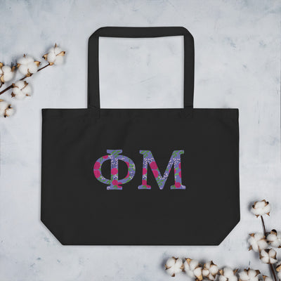 Phi Mu Filled Letters Tote Bag in black shown with cotton blossoms