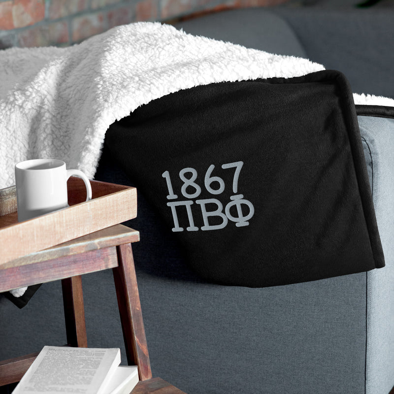 Pi Phi 1867 Plush Embroidered Sherpa Blanket in black on couch