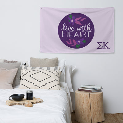 Sigma Kappa Live With Heart Flag with hand-drawn motto design in lavender shown in bedroom setting