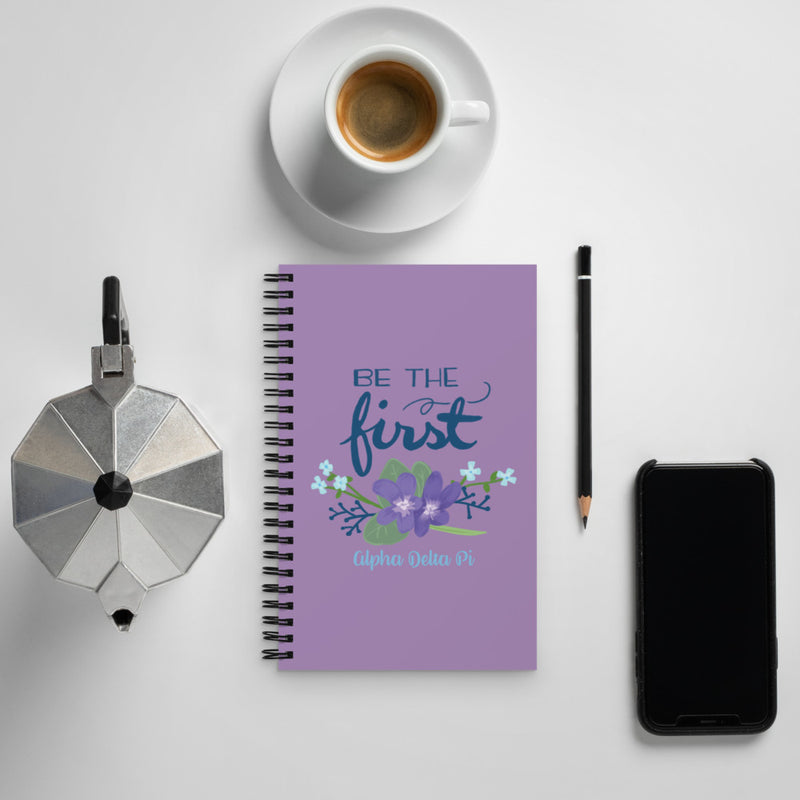 Alpha Delta Pi Be The First Motto Spiral Notebook shown with coffee