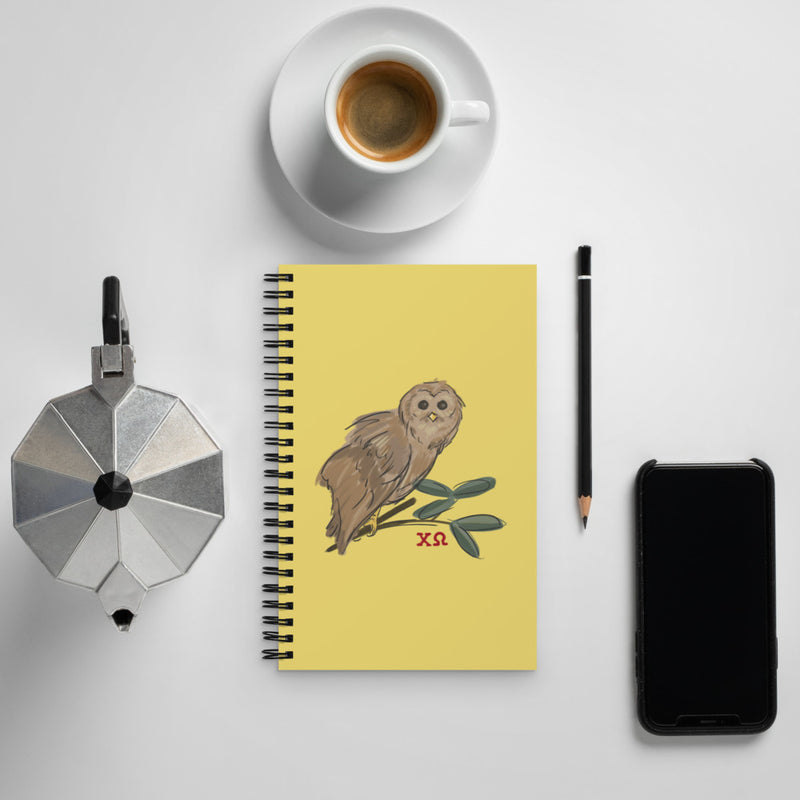 Chi Omega Owl Mascot Spiral Notebook shown with coffee
