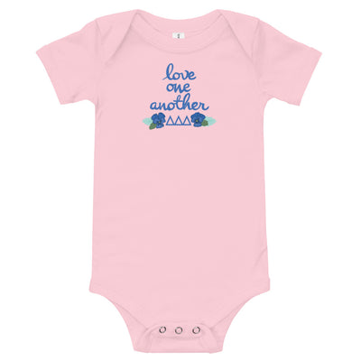 Tri Delta Love One Another Baby Onesie in pink shown flat