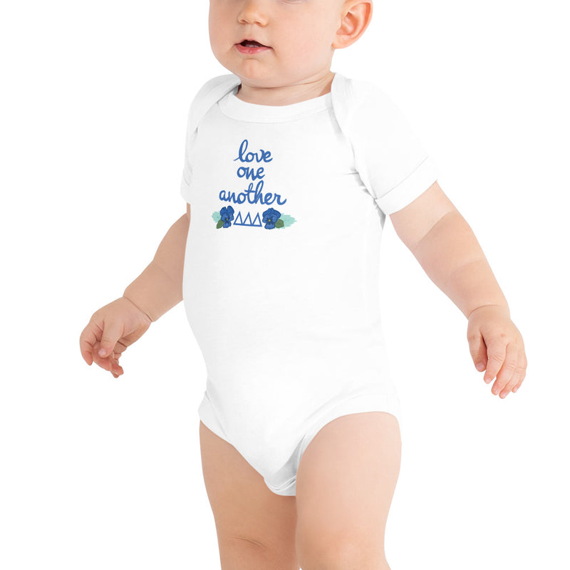 Tri Delta Love One Another Baby Onesie in white shown on toddler model