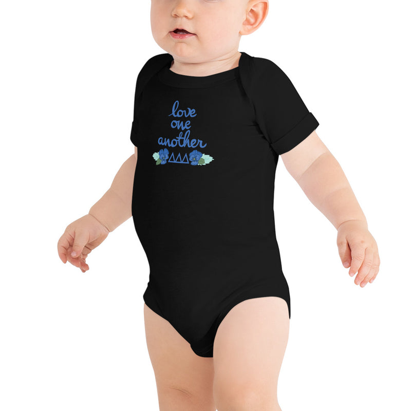 Tri Delta Love One Another Baby Onesie in black shown on toddler model