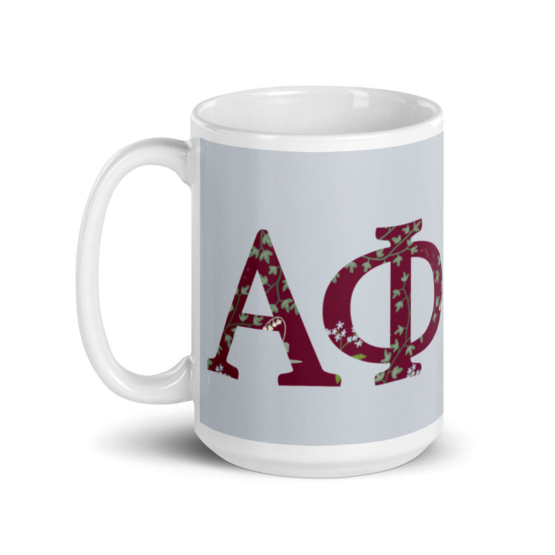 Alpha Phi 15 oz. Greek letters mug in Silver  with floral print filled letters shown with handle on left